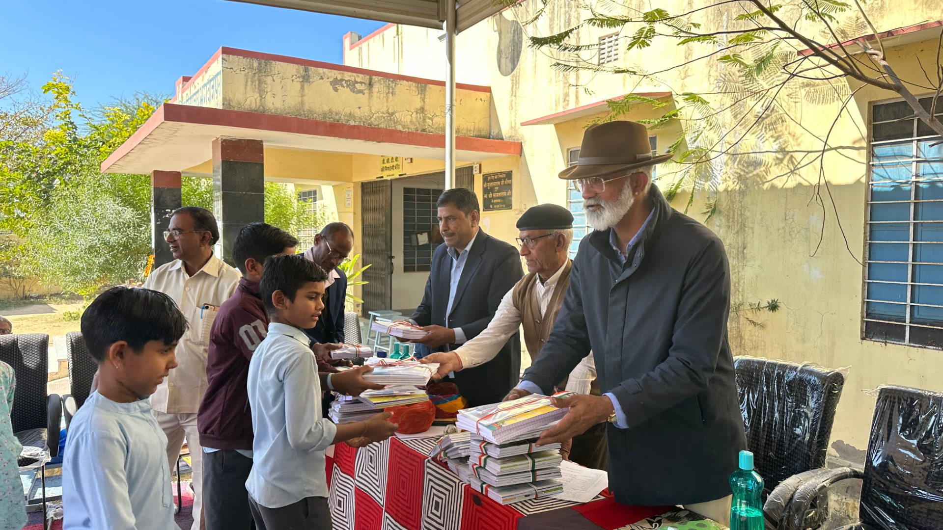 Mr. Madhav Rathore handing out books and stationery to schoolchildren at a village school